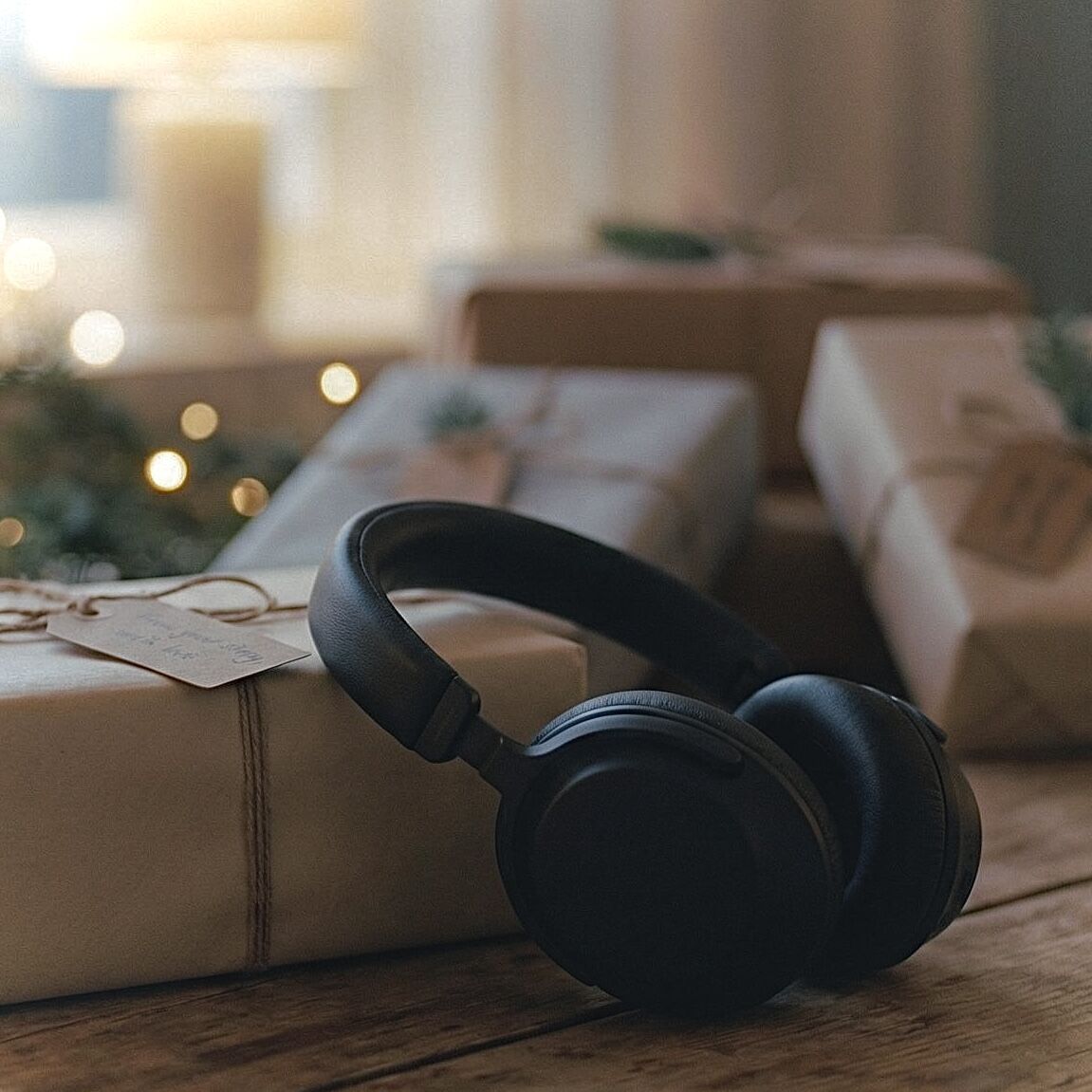 Hörlurar på inslagen julklapp vid granen — personlig julpresent